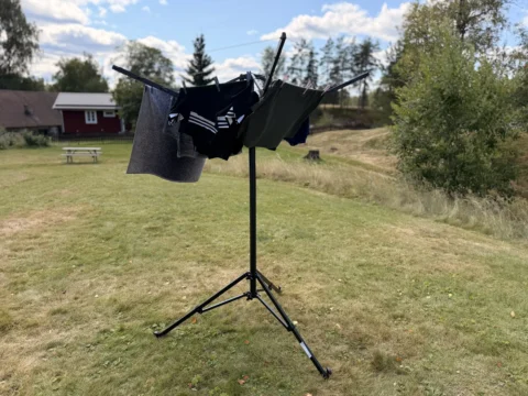 Aufgestellte Pop-up-Wäschespinne von Fritz Berger mit aufgehängter Wäsche auf einer Wiese, im Hintergrund ein rotes Holzhaus in Schweden