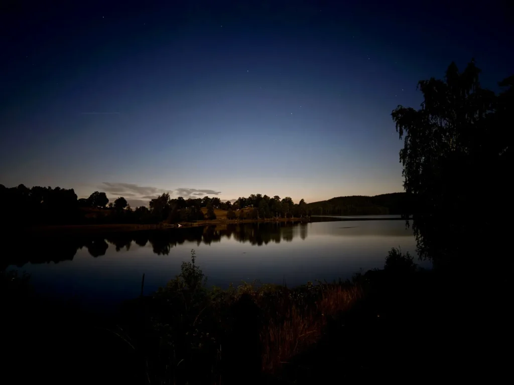 Der Åsunden in der blauen Stunde, am Himmel stehen die ersten Sterne, das gegenüberliegende Ufer spiegelt sich im stillen Wasser.