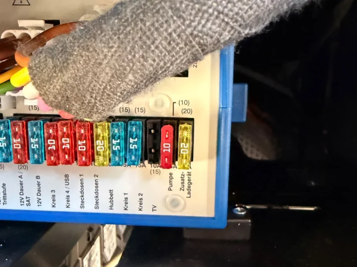 Geöffneter Sicherungskasten im Wohnmobil, der Steckplatz für TV ist leer, daneben stecken die Sicherungen für Pumpe und Zusatz-Ladegerät.