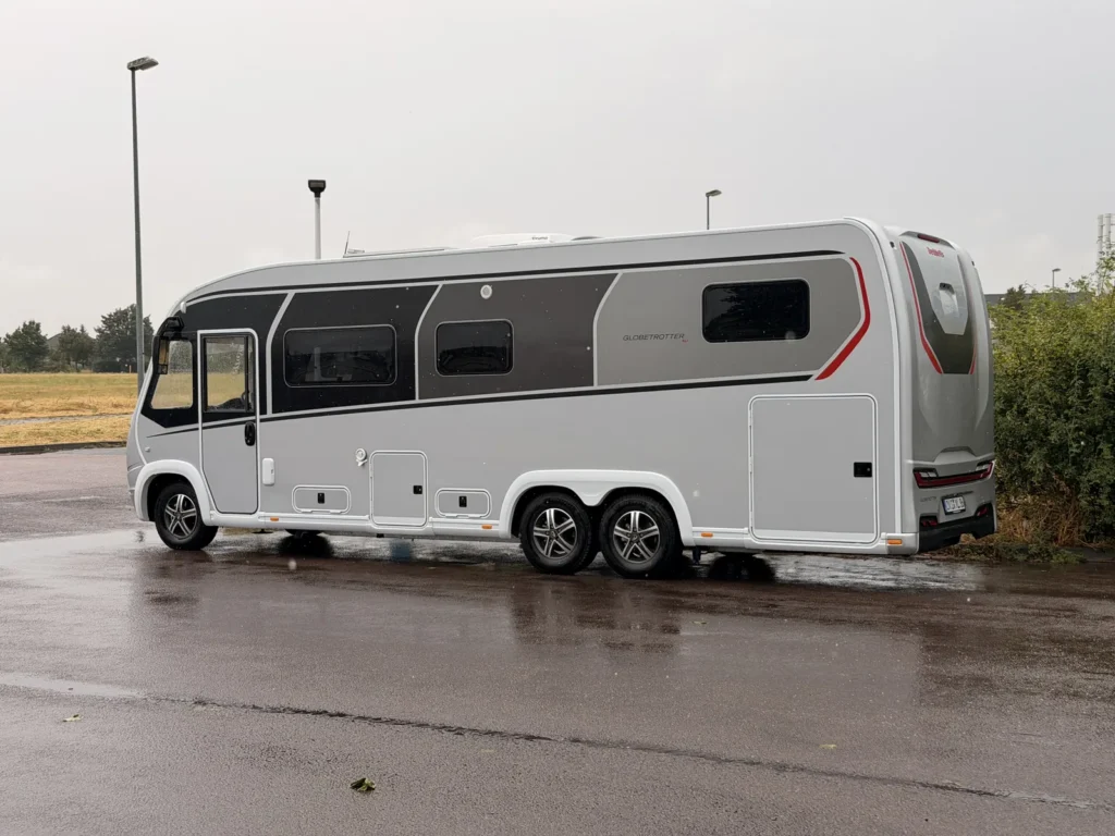 Dethleffs Globetrotter XLi in Silber von der Seite auf einem nassen Rastplatz bei Regen
