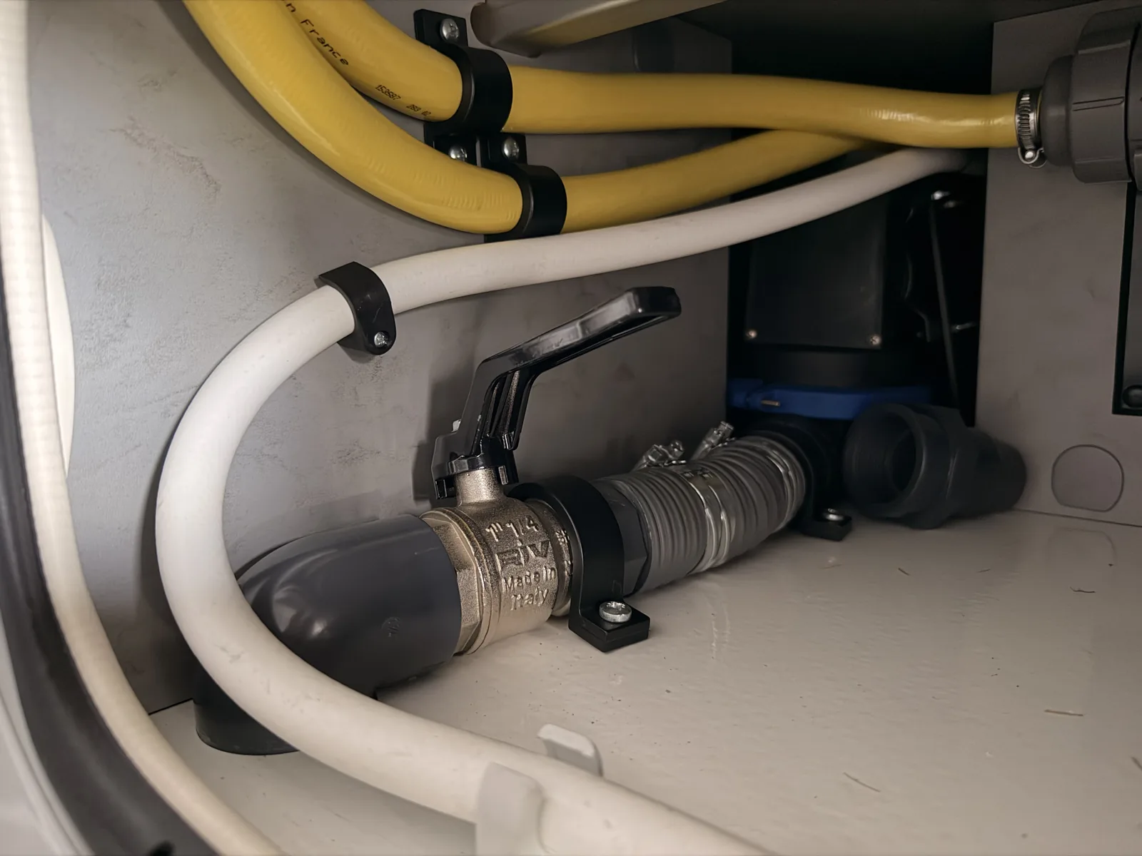 Kugelhahn mit schwarzem Hebel am Ablassrohr im Serviceschacht des Wohnmobils
