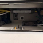 Geöffnete Serviceklappe am Wohnmobil mit Wasserfilter, Ventilen und dem Bedienfeld für den Fäkalientank
