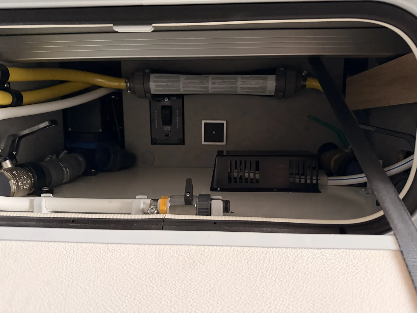 Geöffnete Serviceklappe am Wohnmobil mit Wasserfilter, Ventilen und dem Bedienfeld für den Fäkalientank