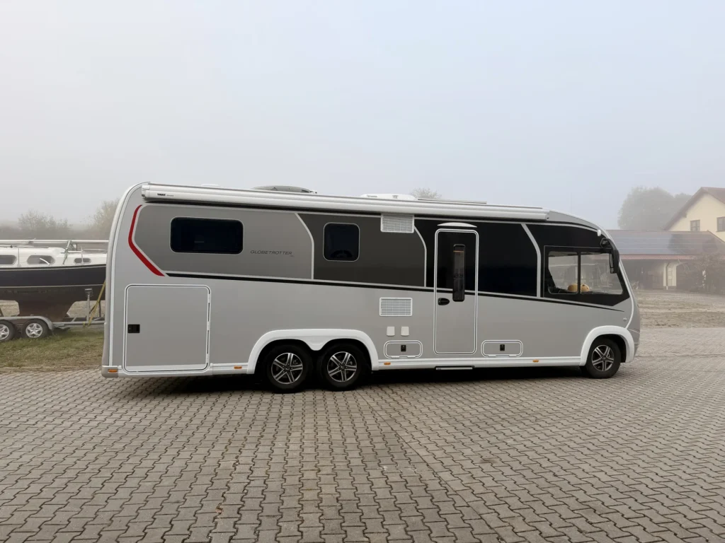 Unser Dethleffs Globetrotter XLi Luna in Seitenansicht auf einem gepflasterten Hof, ringsum dichter grauer Nebel
